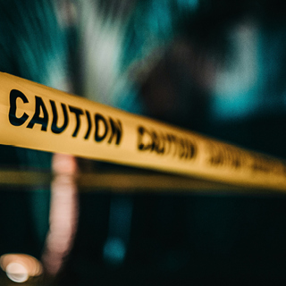 een oranje kleurig politie lint met daarop het woord 'caution'. De banner wordt gebruik bij het artikel van Teeuwissen over oplichting aan deuren 