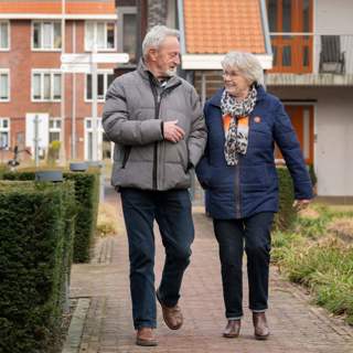 2 bewoners lopen buiten en kijken elkaar lachend aan. Het beeld wordt gebruikt als sfeerbeeld bij een artikel over doorstromen naar een andere woning.